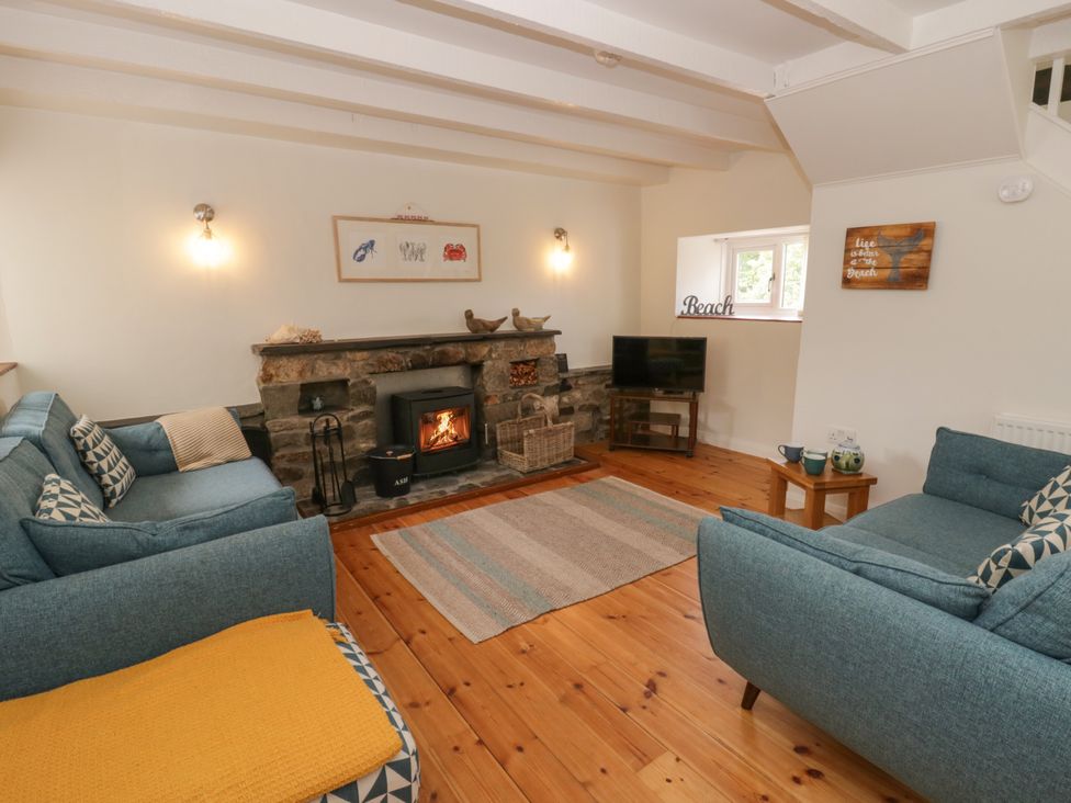 A living room with a fireplace and sofas at Little Barn Cottage in Dinas Cross, Pembrokeshire