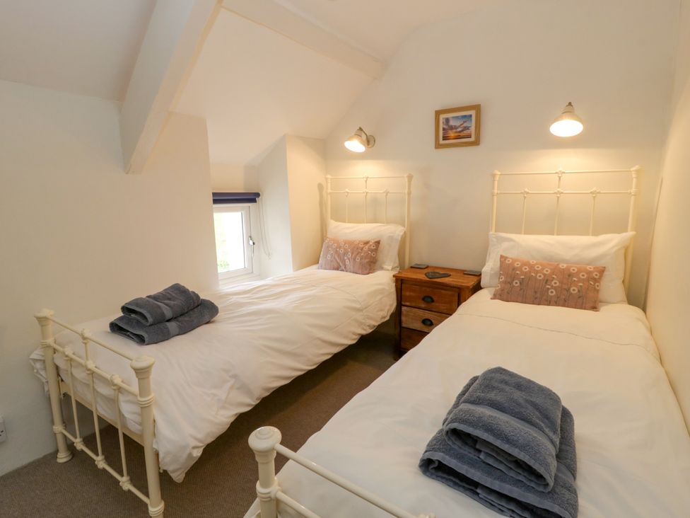 A bedroom with two beds and a bedside table at Little Barn Cottage, Dinas Cross, Pembrokeshire