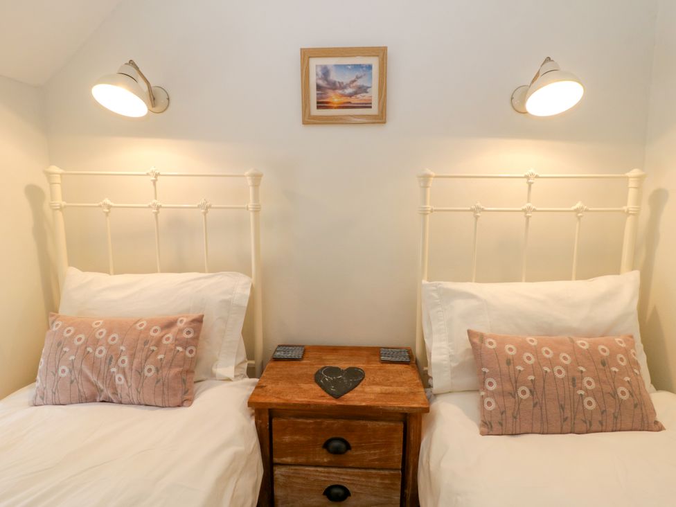 Two beds with pillows and a nightstand at Little Barn Cottage Dinas Cross, Pembrokeshire
