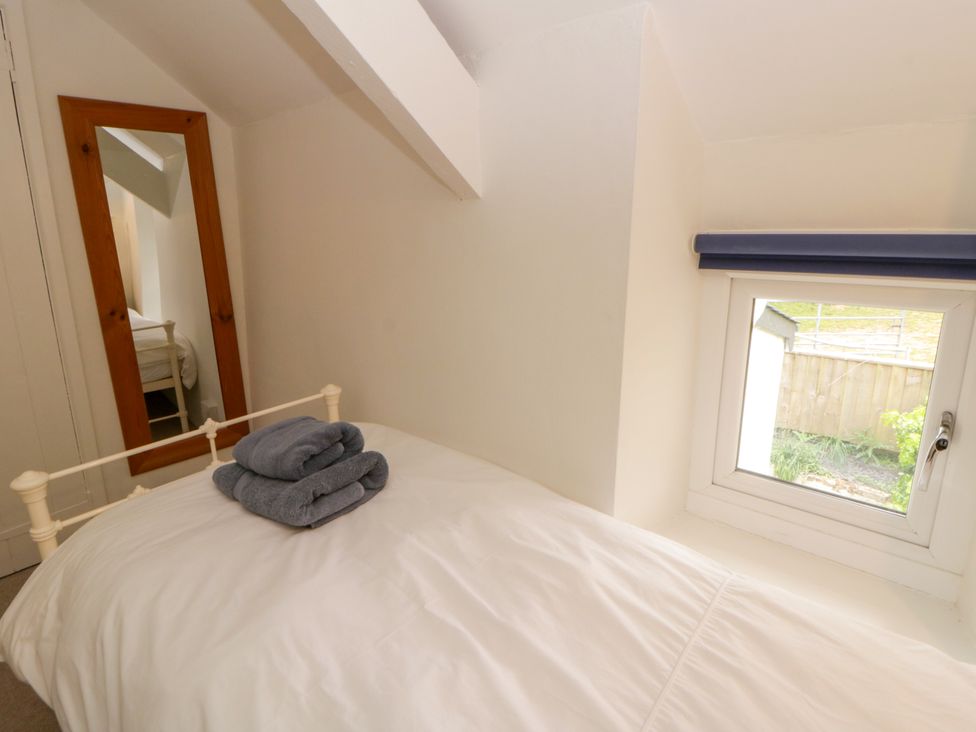 A bedroom with a bed and a mirror at Little Barn Cottage, Dinas Cross, Pembrokeshire