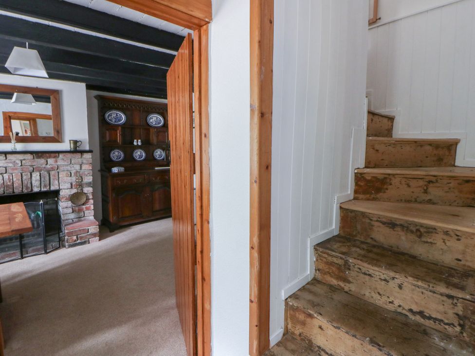 A hallway with wooden stairs and a fireplace at Panteg, Cardigan Llangoedmor Cardigan