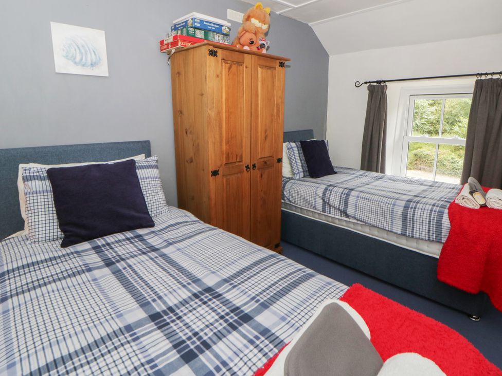 A bedroom with two beds and a wooden wardrobe at Panteg, Cardigan Llangoedmor Cardigan