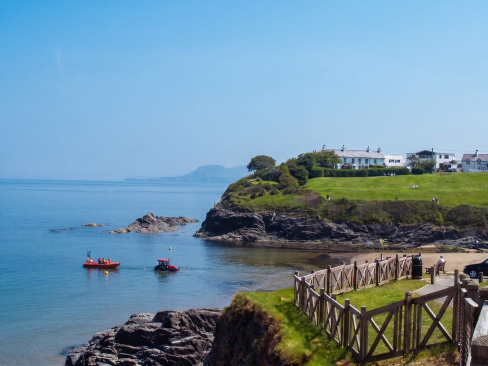 A view of the ocean with boats near a cliff and houses at Beach Retreat in Aberporth