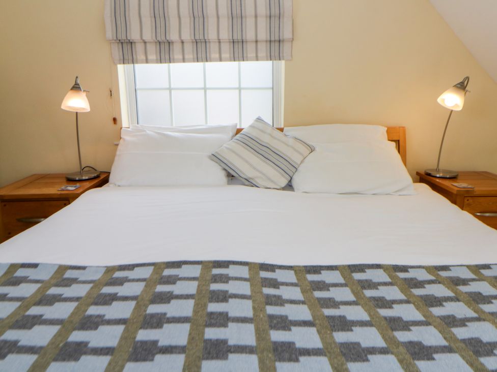 A bedroom with a bed and nightstands at Beach Retreat in Aberporth