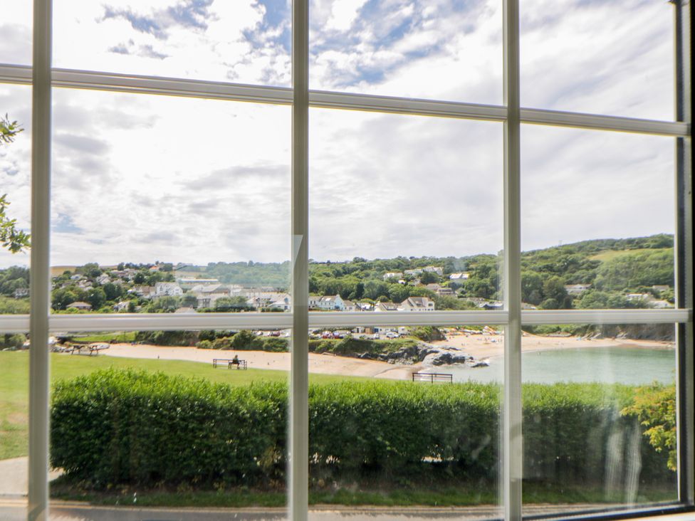 A view of a beach and houses through a window at Beach Retreat in Aberporth