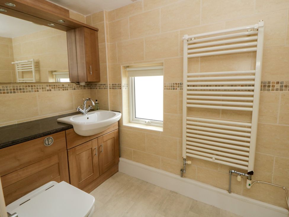 A bathroom with a sink, toilet and mirror at Beach Retreat in Aberporth