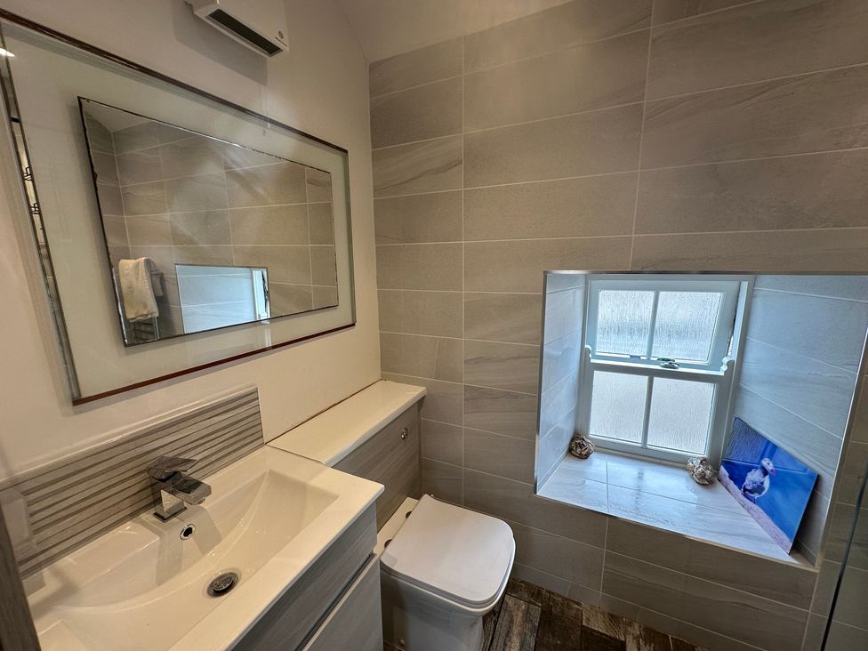 A bathroom with a sink, mirror, and toilet at Beach Cottage in Little Haven, Pembrokeshire