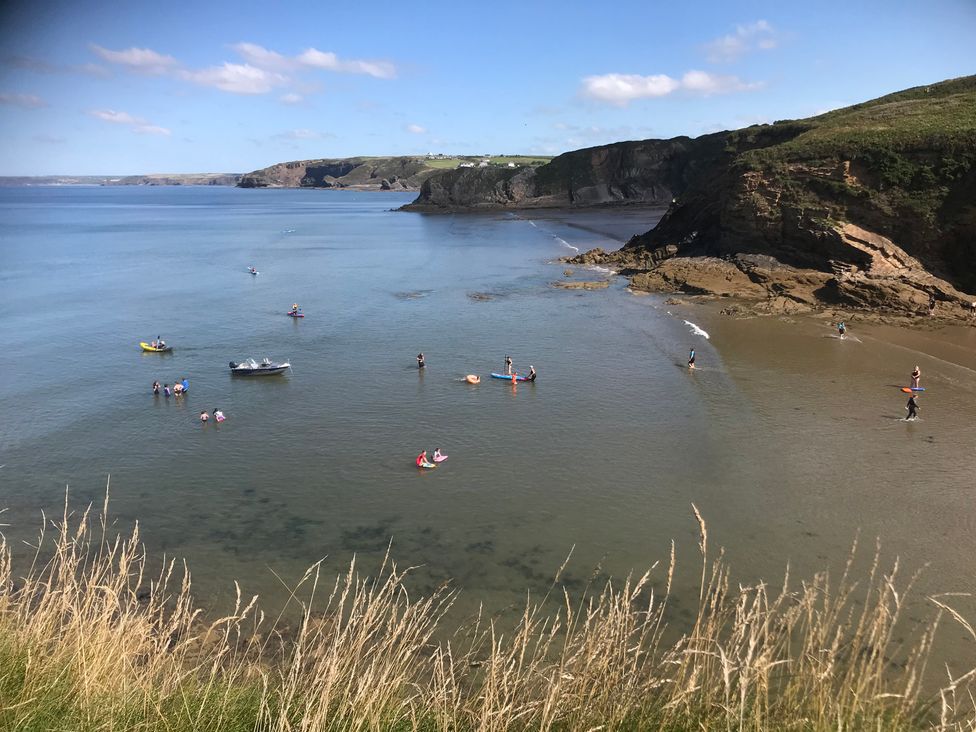 A beach with people and boats at Beach Cottage in Little Haven, Pembrokeshire
