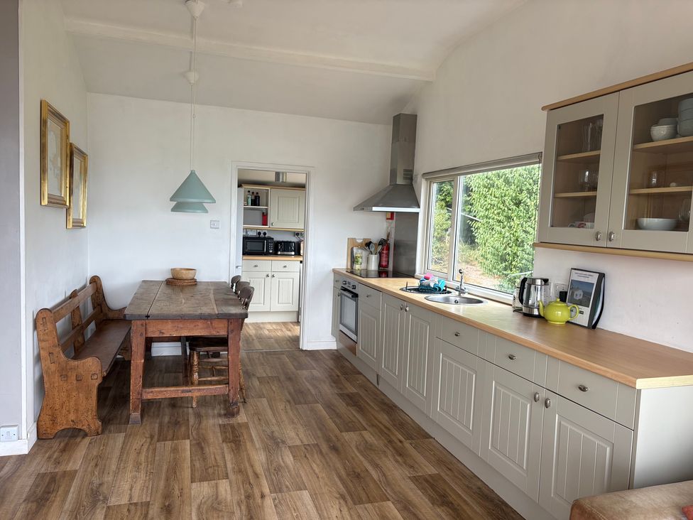 A kitchen with a table and benches at Beach Cove in Freshwater East, Pembrokeshire
