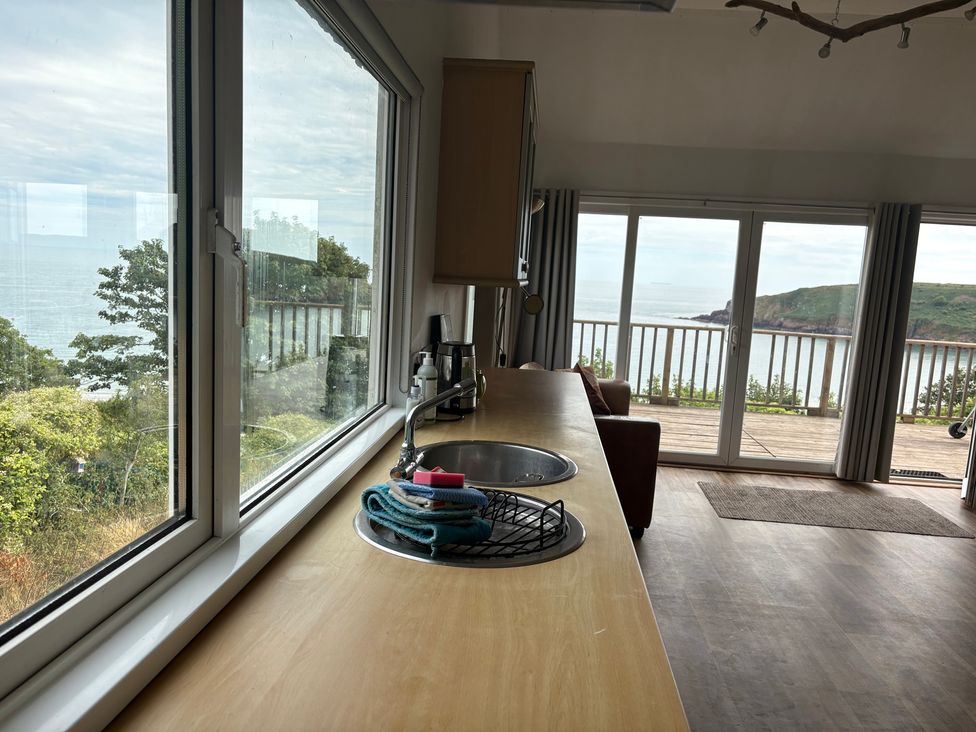 A kitchen with a sink and sea view at Beach Cove Freshwater East Pembrokeshire
