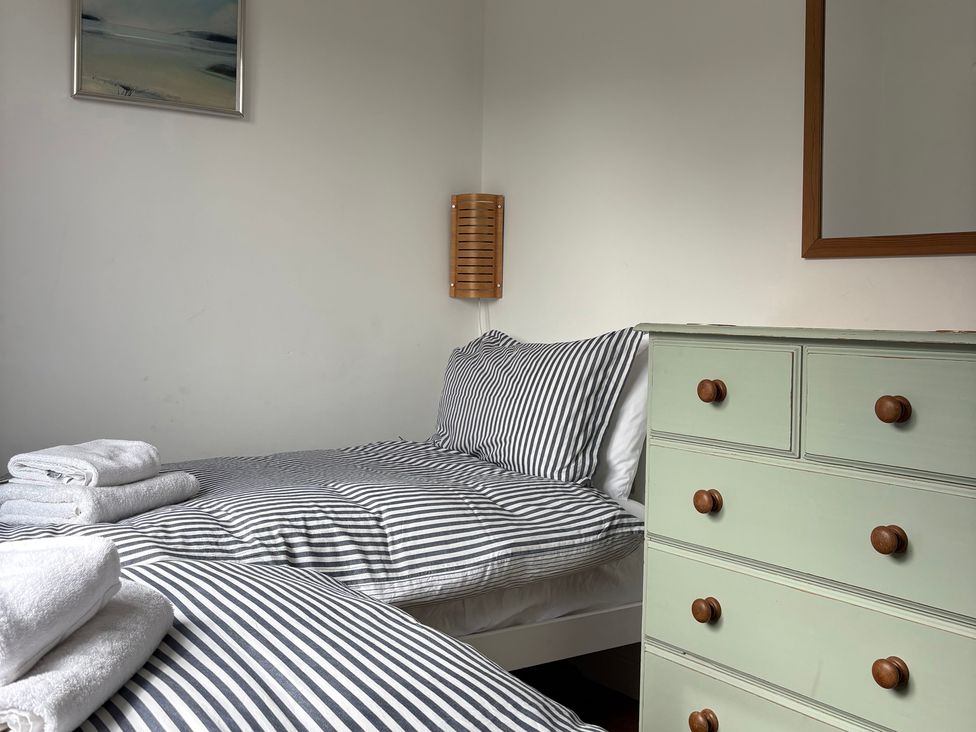 A bedroom with two beds and a dresser at Beach Cove, Freshwater East, Pembrokeshire