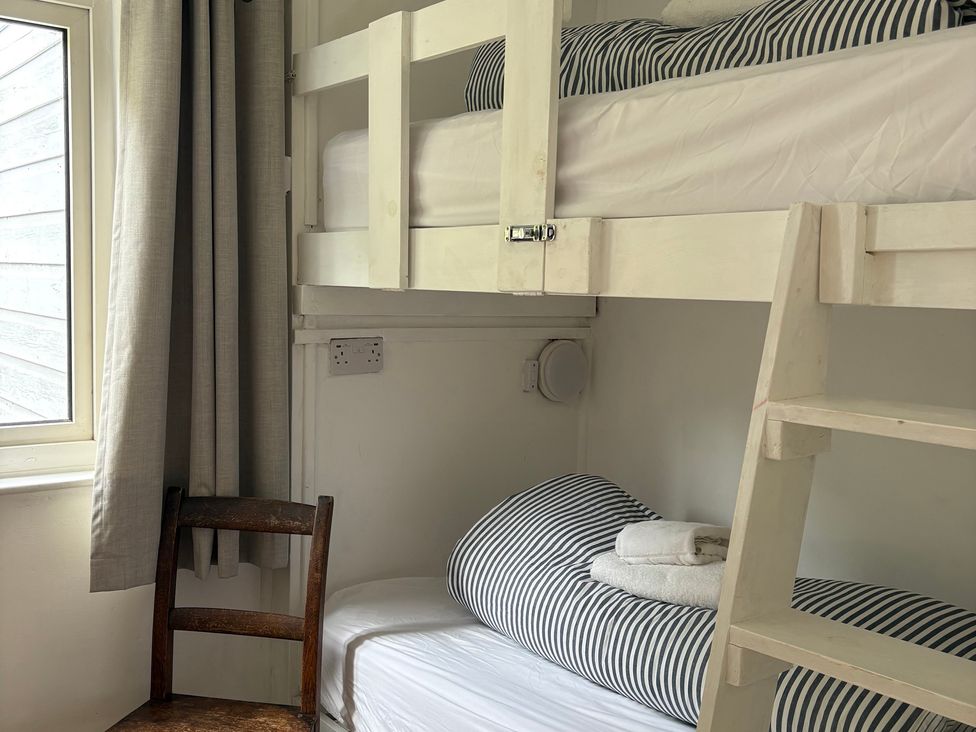 A bedroom with bunk beds and a chair at Beach Cove in Freshwater East, Pembrokeshire