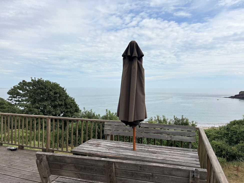 An outdoor seating area with a table and umbrella at Beach Cove, Freshwater East, Pembrokeshire