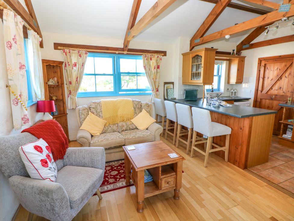 A living room with armchair sofa coffee table and kitchen counter with bar stools at Casa Mia Strumble Head Goodwick