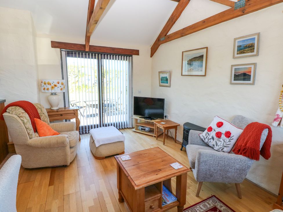 A living room with armchairs a wooden coffee table a television and framed pictures on the wall at Casa Mia in Strumble Head Goodwick
