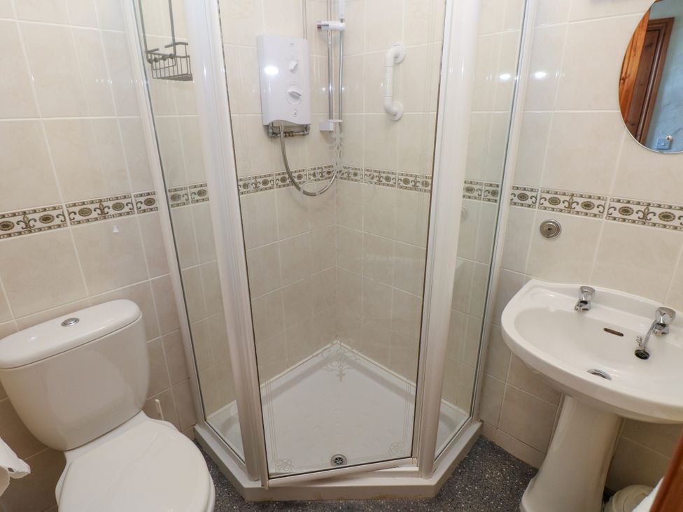 A bathroom with a toilet a corner shower enclosure and a pedestal sink at Casa Mia in Strumble Head Goodwick