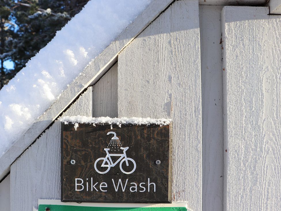 A Bike Wash sign attached to a wooden structure with snow on the roof at Osprey Apartment in Aviemore