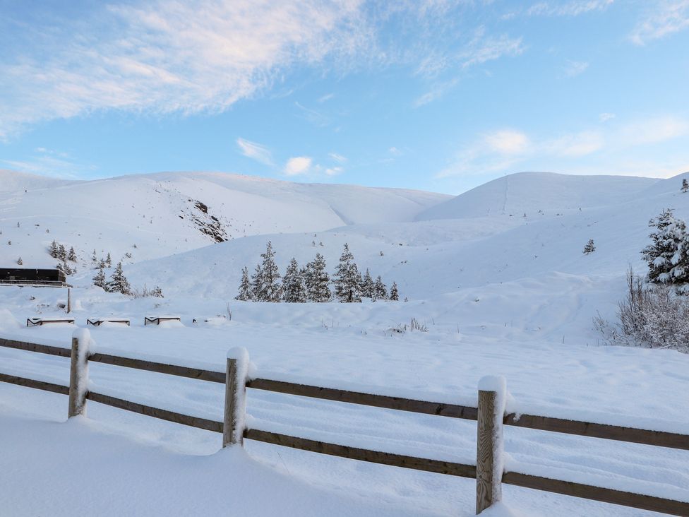A snowy landscape with mountains and a wooden fence at Osprey Apartment in Aviemore