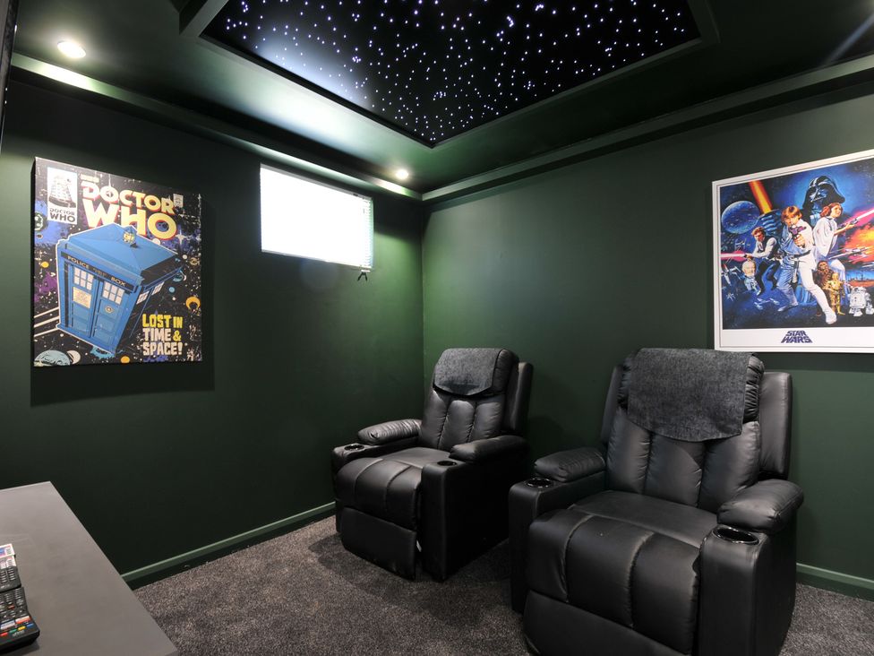 A home theater with recliner chairs and sci-fi posters at The Hideout in Lanreath