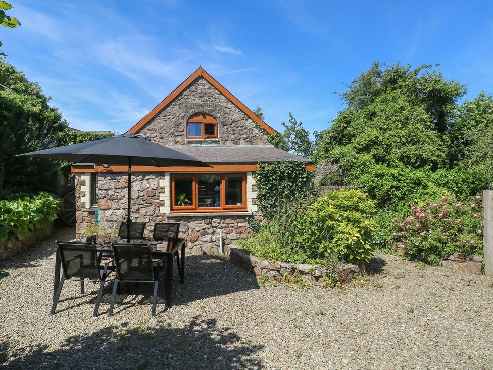 A house with a table and chairs under an umbrella at Barn Court Cottage Narberth, Pembrokeshire