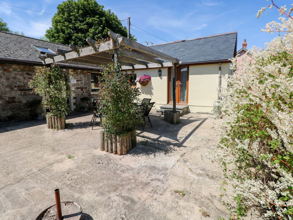 An outdoor area with a pergola and seating at Stoney Cottage in Narberth, Pembrokeshire