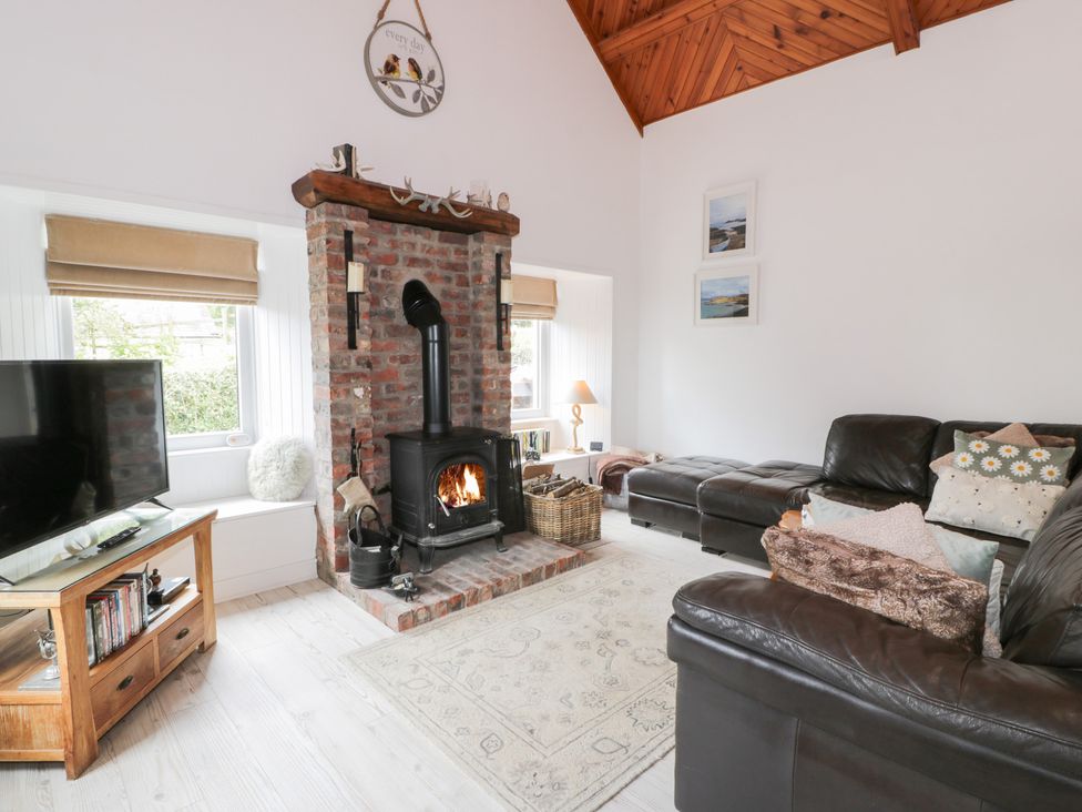 A living room with a fireplace and television at The Barn in Rockcliffe