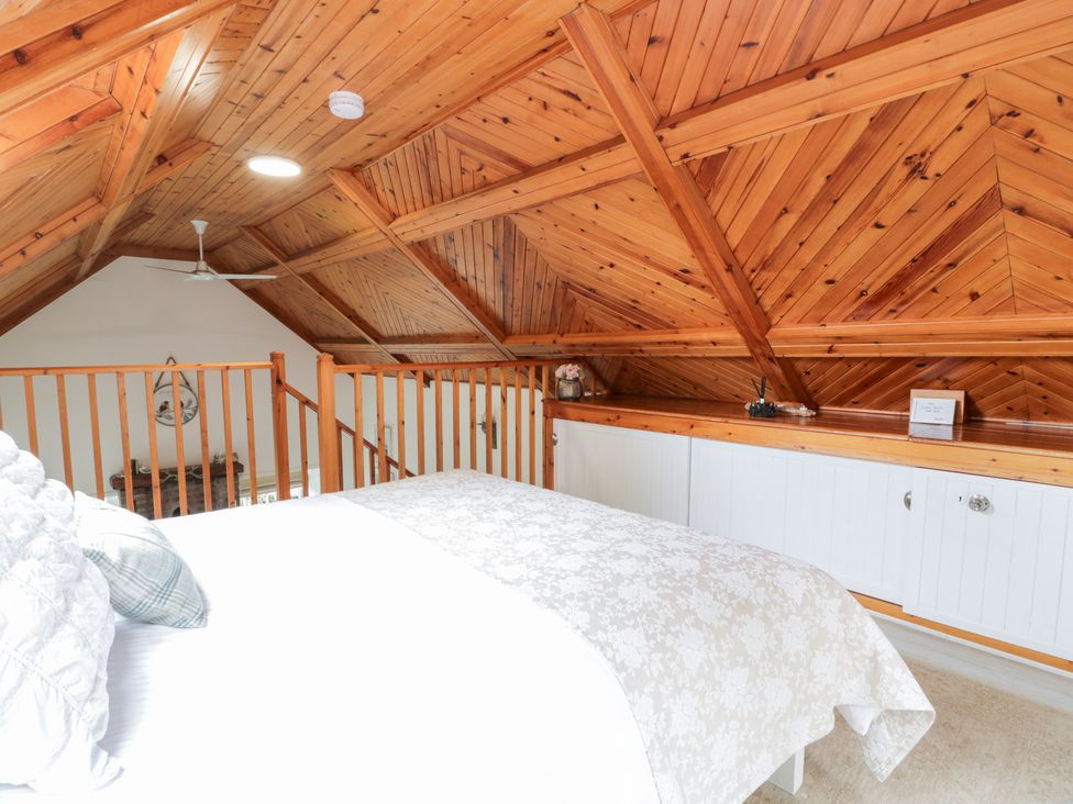 A loft with a bed and wooden ceiling beams at The Barn in Rockcliffe