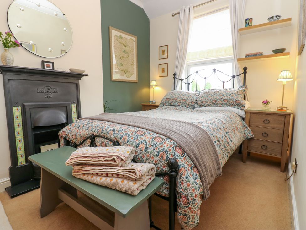 A bedroom with a bed, bedside table, and mirror at 4 Ford Street in Lanchester