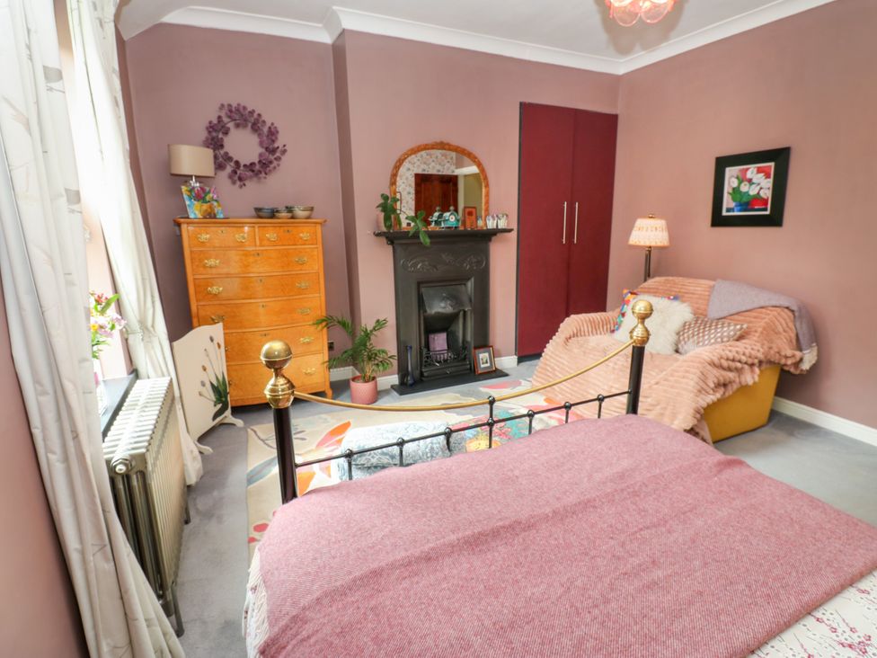A bedroom with a bed, sofa, dresser, and fireplace at 4 Ford Street in Lanchester