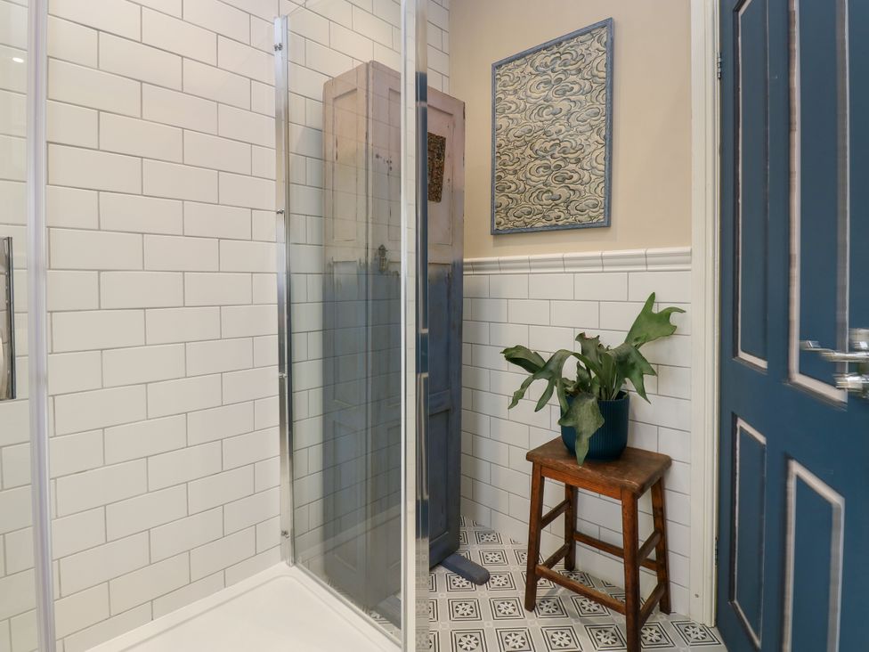A bathroom with a shower and a plant on a stool at 4 Ford Street Lanchester