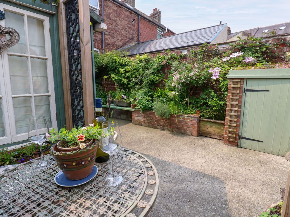 A garden with a table, potted plant, wine bottles, and a shed at 4 Ford Street Lanchester