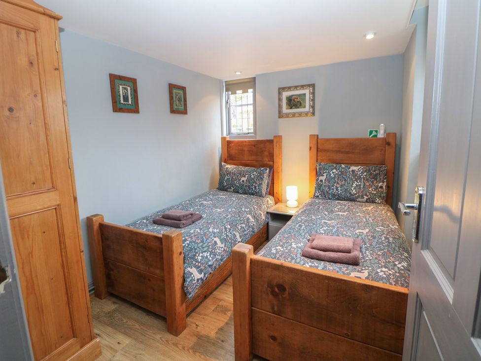 A bedroom with two beds, a nightstand, and a wardrobe at Nine Ladies in Birchover