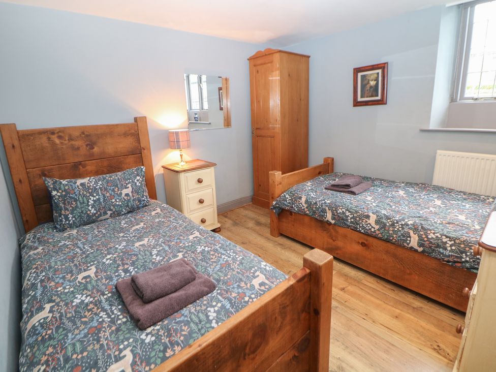 A bedroom with two beds and wooden furniture at Nine Ladies in Birchover