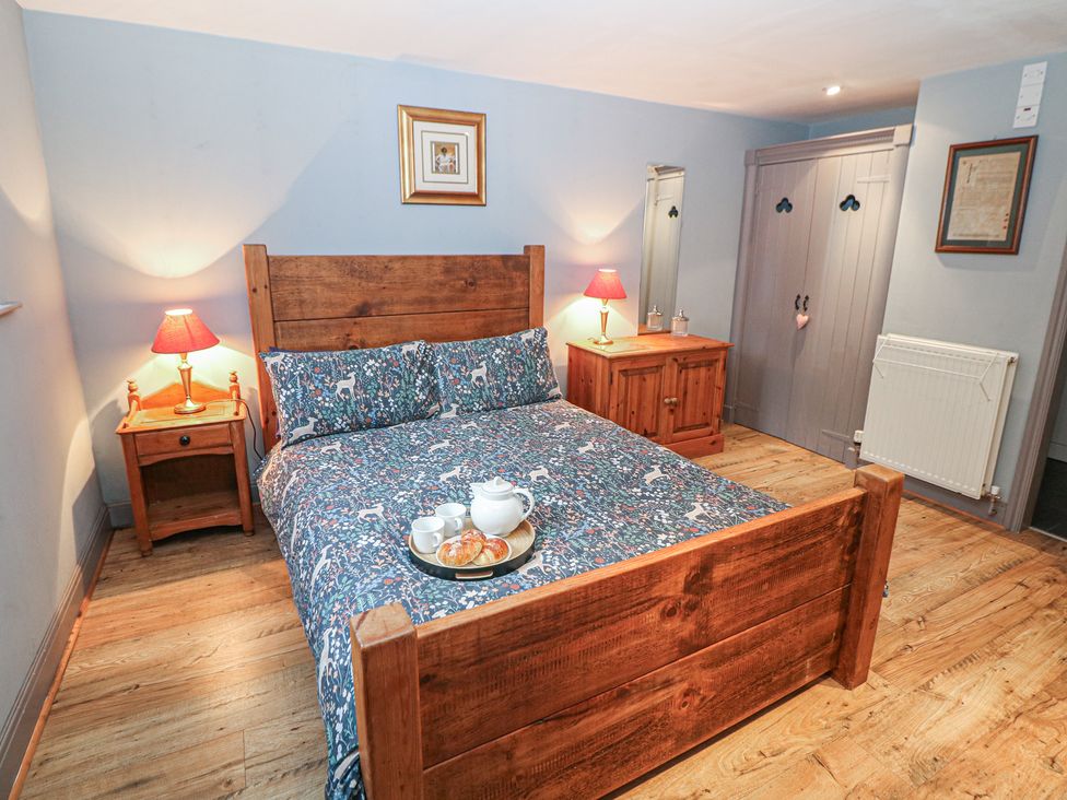 A bedroom with a wooden bed and bedside table at Nine Ladies in Birchover