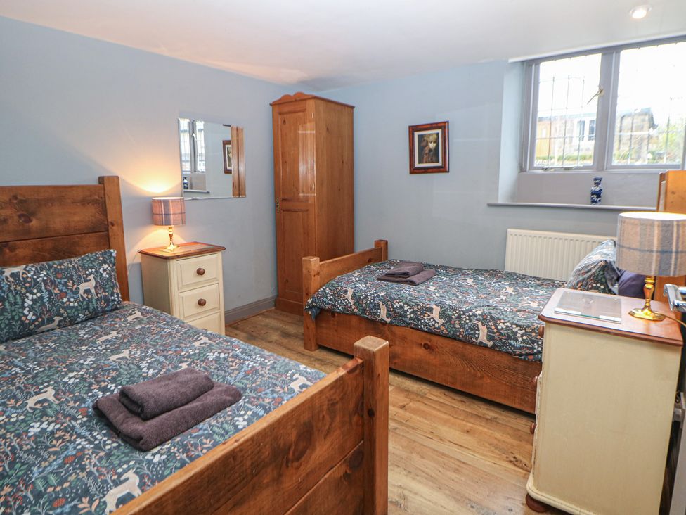 A bedroom with two beds, a nightstand, and a wardrobe at Nine Ladies in Birchover