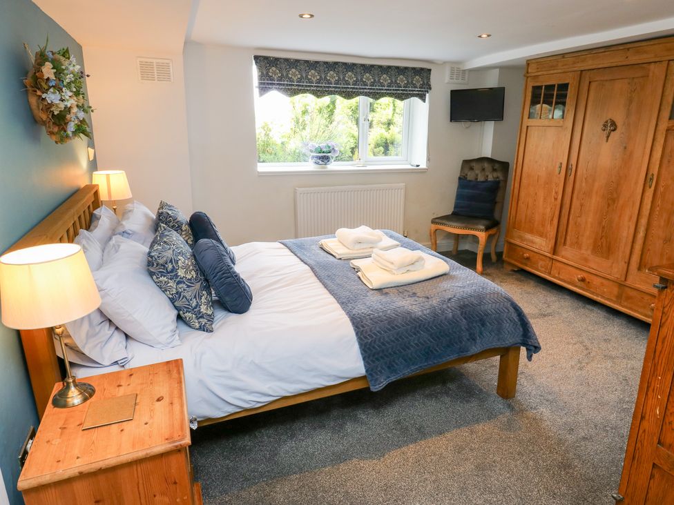 A bedroom with a bed and wardrobe at The Thyme House in Haworth