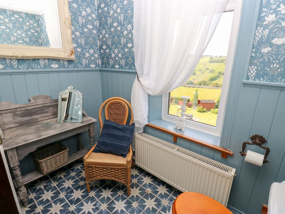 A bathroom with a mirror and chair at The Thyme House in Haworth