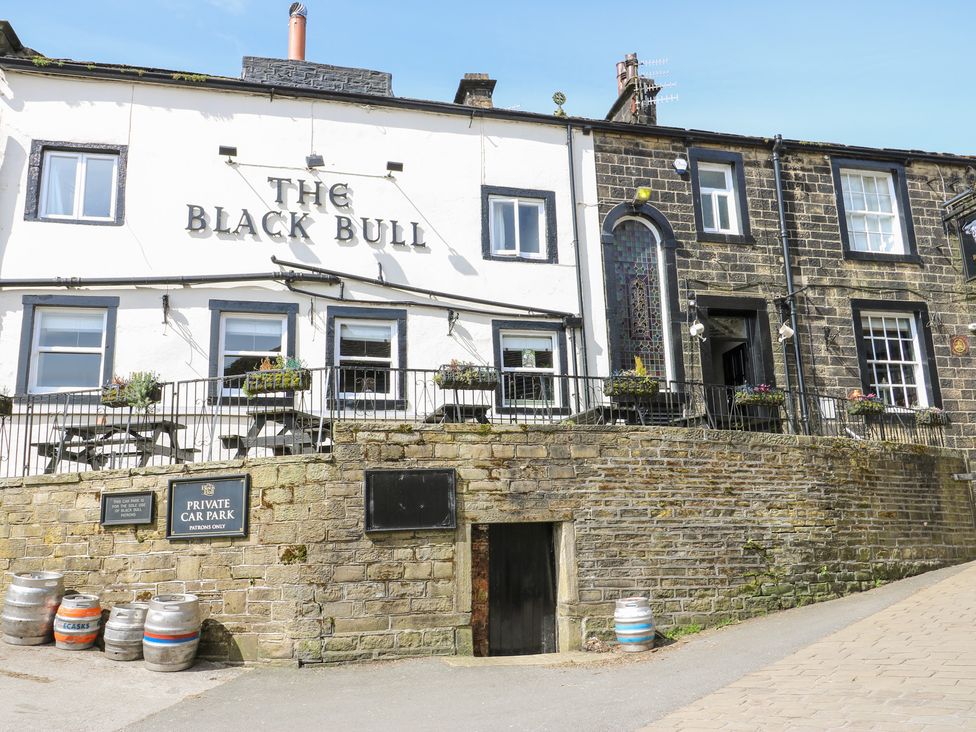 An exterior view of a building with a sign and benches at The Black Bull in Haworth