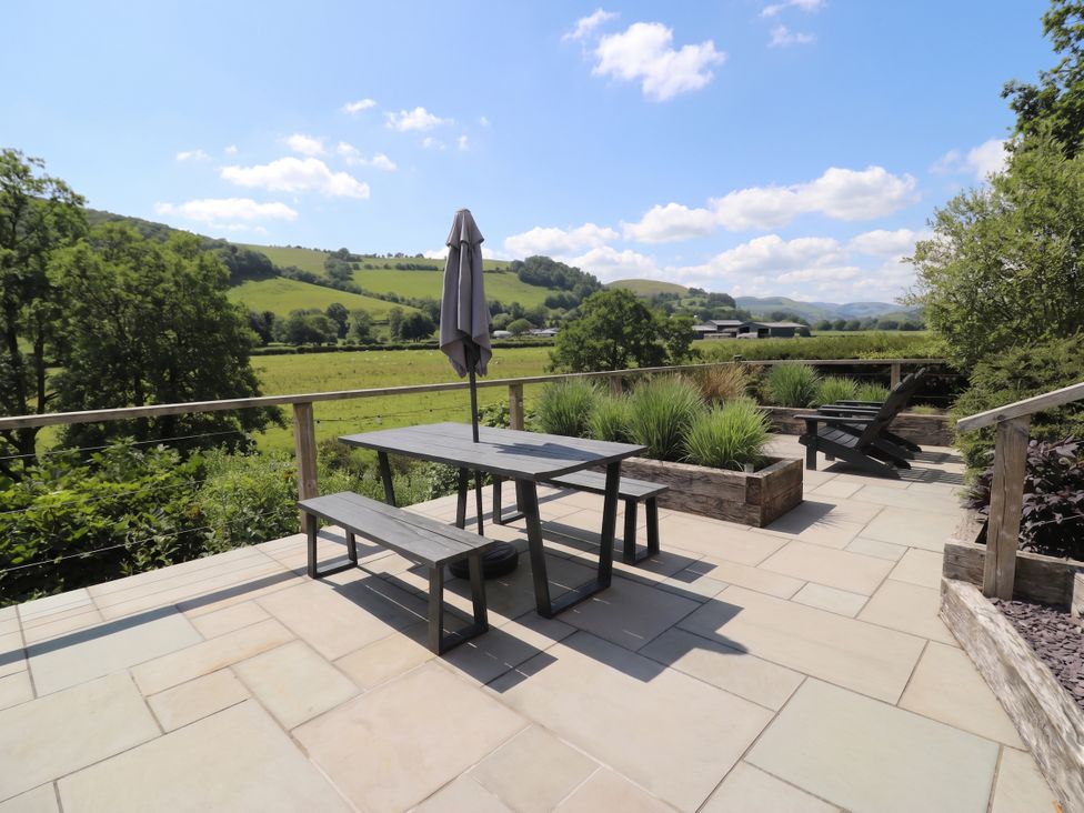 An outdoor seating area with a table and benches at Pengeulan, Cemmaes