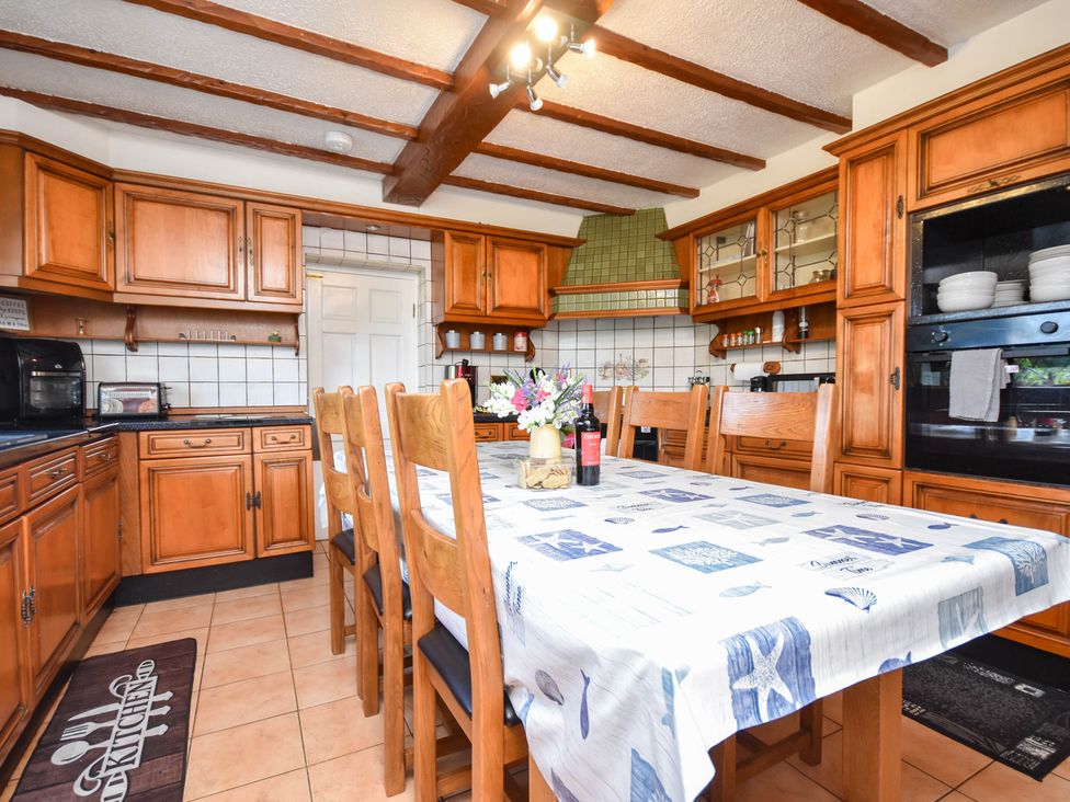 A kitchen with wooden cabinets and a dining table at Freshwinds in Market Drayton