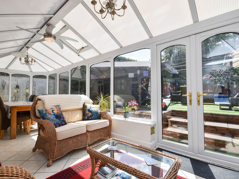 A conservatory with a sofa and dining table at Freshwinds in Market Drayton