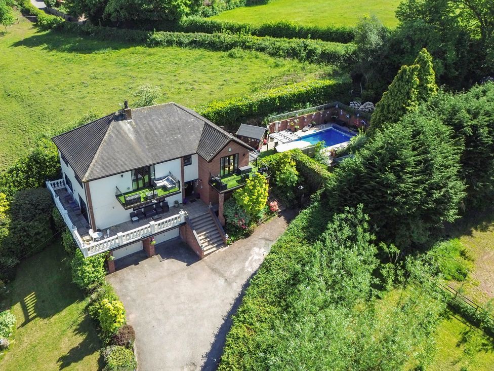 An outdoor view of a house with a garden and swimming pool at Freshwinds in Market Drayton