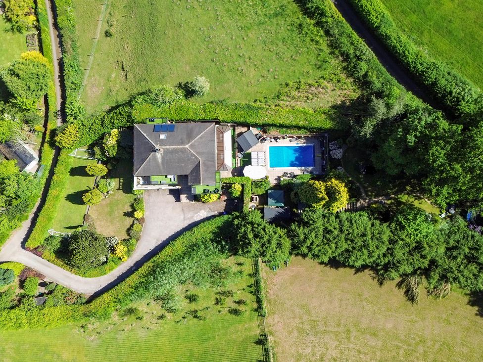 An aerial view of a house with a swimming pool and garden at Freshwinds in Market Drayton