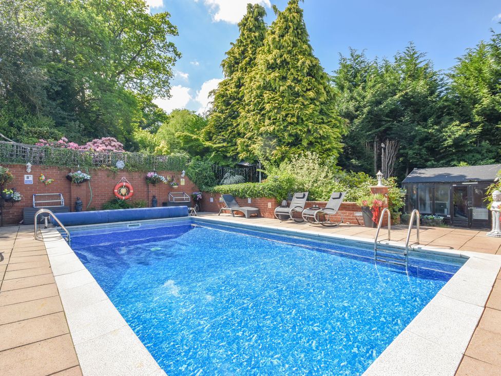 A swimming pool surrounded by patio and garden at Freshwinds in Market Drayton