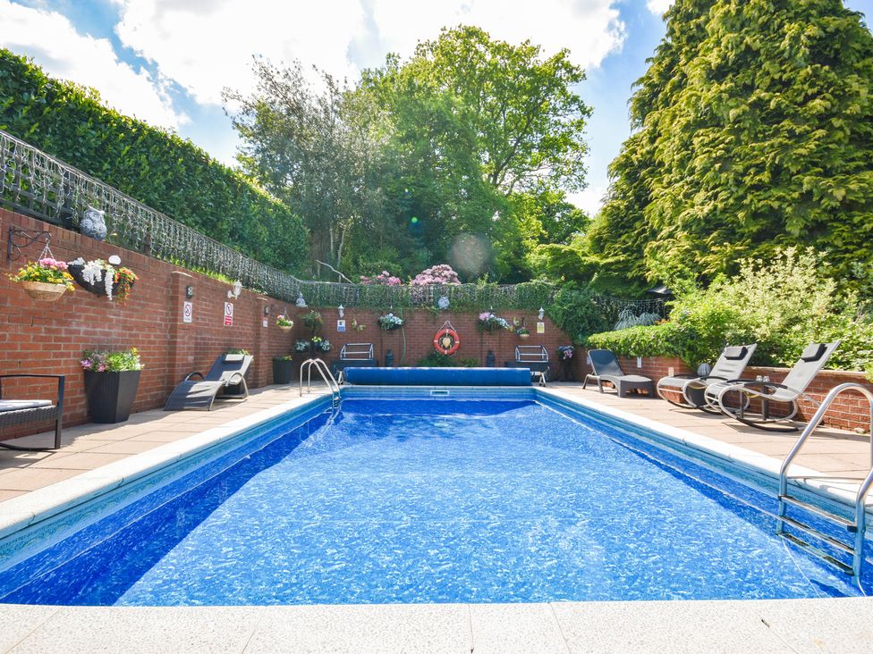 An outdoor swimming pool with lounge chairs at Freshwinds Market Drayton