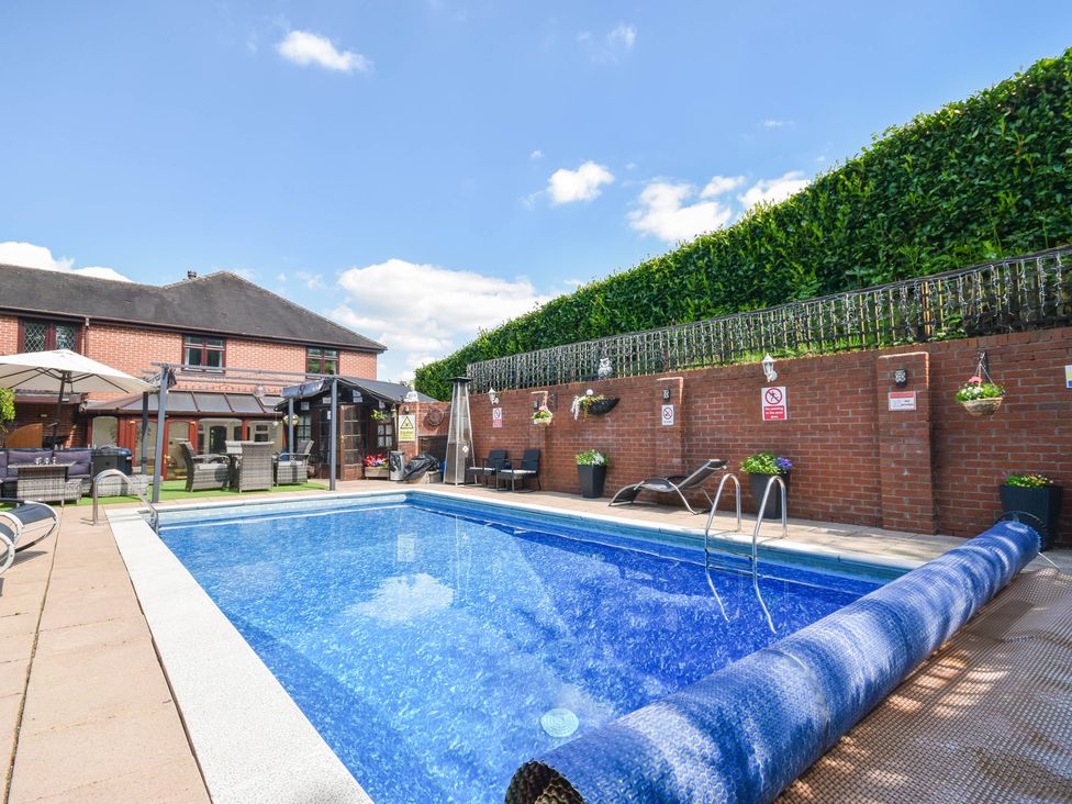 A swimming pool with umbrellas and sun loungers at Freshwinds in Market Drayton