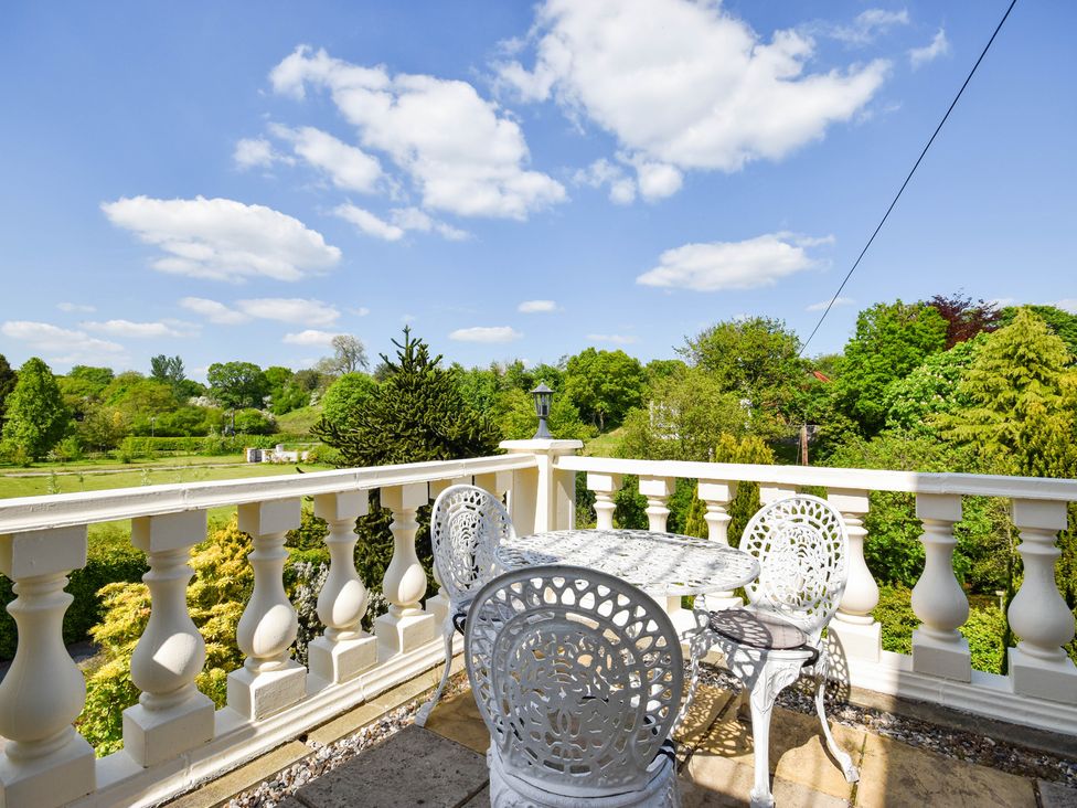 A balcony with table and chairs overlooking greenery at Freshwinds in Market Drayton