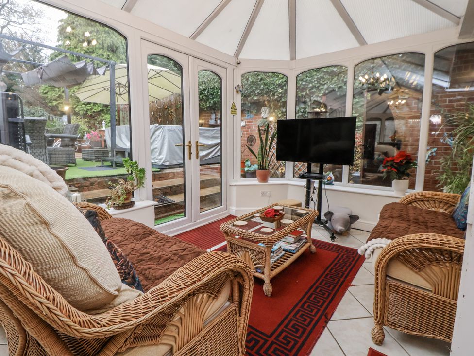 A conservatory with wicker furniture and a television at Freshwinds in Market Drayton