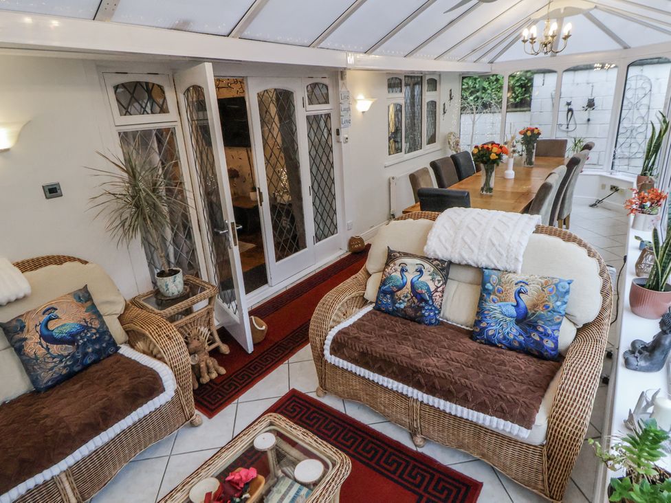A conservatory with a sofa and dining area at Freshwinds in Market Drayton
