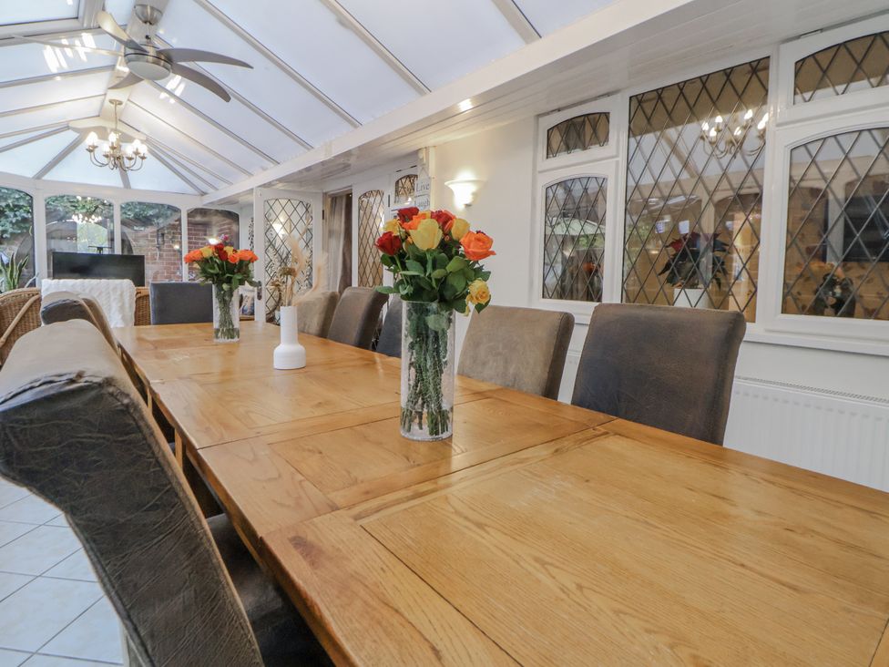 A conservatory with a wooden dining table and chairs at Freshwinds Market Drayton